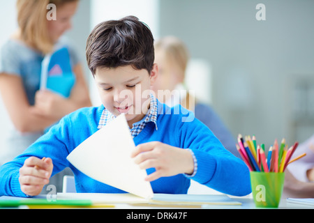 Porträt von niedlichen Schüler sitzen im Unterricht auf Grund seiner Klassenkameraden Stockfoto