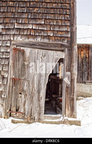 Die defekte Tür und verwitterte Fassade einer alten verlassenen Scheune in New Hampshire. Stockfoto