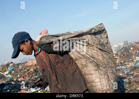 Ein Kind Arbeiter junge trägt große meschotschek voller Müll auf der giftigen Stung Meanchey Deponie in Phnom Penh, Kambodscha. Stockfoto