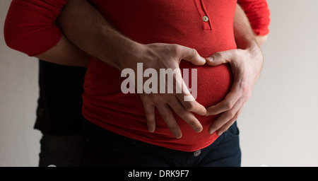 Schwangere paar mit die Hände des Mannes eine Herzform auf die Frau Bauch machen. Stockfoto