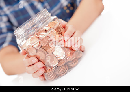 Junge Frau/Mädchen mit ihren Händen hält einen große Einsparungen Glas voller britische Kupfermünzen. Stockfoto