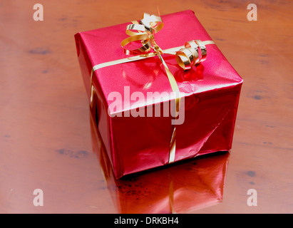 Geschenk verpackt in glänzend rotem Papier und gold string Stockfoto