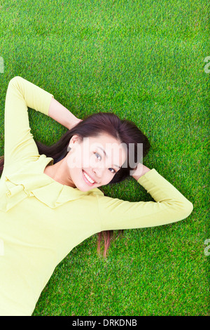 schöne junge Frau, die Festlegung auf Grünland im park Stockfoto