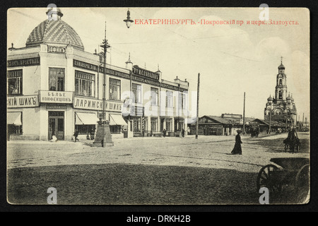 Pokrovsky Prospekt Avenue und die große Zlatoust Kirche in Jekaterinburg, Russisches Reich. Schwarz-Weiß-Vintage-Fotografie des russischen Fotografen Nikolai Vwedensky datiert vom Anfang des 20. Jahrhunderts, ausgestellt in der russischen Vintage-Postkarte von M.S. Semkov, Jekaterinburg. Text auf Russisch: Jekaterinburg. Pokrovsky Prospekt Avenue und die Zlatoust Kirche. Auf dem Bild ist ein Geschäft mit Damenunterbekleidung mit dem Namen 'Parisian Chic' zu sehen. Die große Zlatostkirche im Hintergrund wurde von den Bolschewiki in den 1930er Jahren abgerissen und Anfang des 21. Jahrhunderts restauriert. C Stockfoto