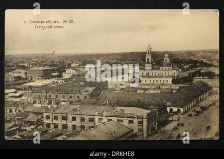 Kaufmannsgericht (Gostiny Dvor) und der Domplatz in Jekaterinburg, Russisches Reich. Schwarz-Weiß-Vintage-Fotografie eines unbekannten Fotografen aus dem Anfang des 20. Jahrhunderts, herausgegeben in der russischen Vintage-Postkarte von A.S. Suvorin, Jekaterinburg. Text auf Russisch: Jekaterinburg. Handelsgericht. Blick vom Glockenturm der Großen Zlatoust Kirche. Im Hintergrund ist die Kathedrale der Kreuzerhöhung auf dem Domplatz zu sehen. Die Kathedrale wurde in den 1930er Jahren von den Bolschewiki abgerissen. Der Gostiny Dvor ist ein historischer russischer Begriff für einen Indoor-Markt, o Stockfoto