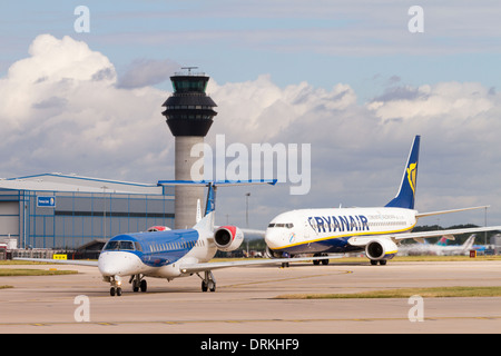 BMI Embraer taxis vorbei Kontrollturm für Take off am Flughafen Manchester Stockfoto