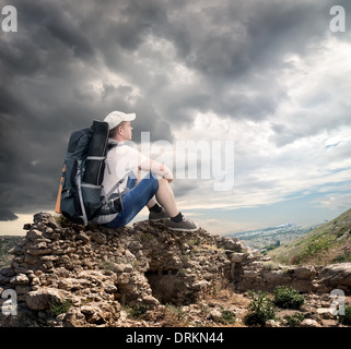 Touristen sitzen auf den Felsen unter bewölktem Himmel Stockfoto