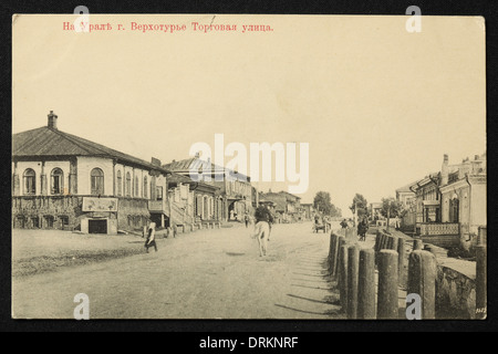 Torgowaja Straße in der Stadt Werchoturye im Ural, Russisches Reich. Schwarz-Weiß-Vintage-Fotografie eines unbekannten Fotografen aus dem Anfang des 20. Jahrhunderts in der russischen Vintage-Postkarte ausgestellt. Text auf Russisch: Im Ural. Werchoturye. Torgovaya Street (Handelsstraße). Werchoturye ist die älteste russische Stadt in der Region des Urals, am Fluss Tura, etwa 306 km von Jekaterinburg in Swerdlowsk Region, Russland. Mit freundlicher Genehmigung der Azoor Postcard Collection. Stockfoto