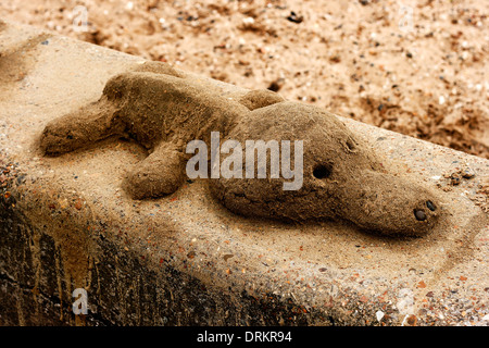 Eine Sandskulptur eines Hundes oder Krokodil, sitzt auf einem Deich am Strand in Southend-on-Sea, Essex, England. Stockfoto