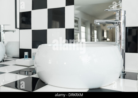 Moderne weiß Oval Waschbecken im Bad mit karierten schwarzen und weißen Fliesen. Stockfoto