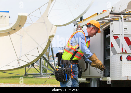 Kommunikation-Ingenieur immer Ausrüstung von Lastwagen mit Satelliten-Antenne im Hintergrund Stockfoto