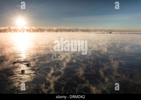 Die Sonne erhebt sich ein Band von Lake-Effect Cloud und dampfenden Wasser des Lake Ontario unter einem kalten Wetter polare Luftmasse Stockfoto