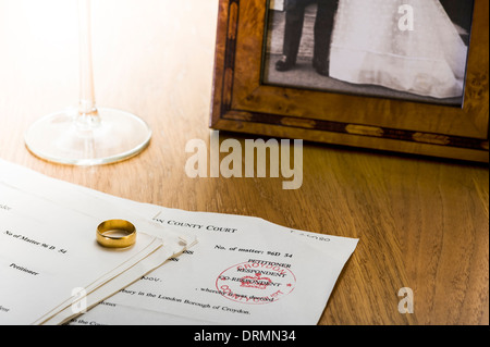 Scheidung-Dokumente auf einem Tisch mit Ehering und Hochzeitsfoto. Stockfoto