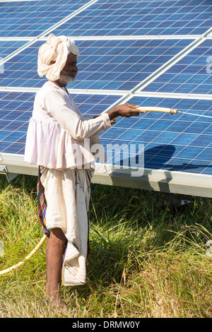 Ein Mann verwendet einen Schlauch, um Staub von Sonnenkollektoren an Asiens größte solar Popwer Station waschen Stockfoto