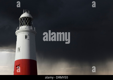 Ein heller Leuchtturm steht in der Sonne während ein Sturms dahinter baut. Viel Platz für das Hinzufügen von kopieren. Stockfoto
