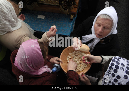 Orthodoxe Gläubige nehmen die Lämmer, quadratische Portionen Brot aus der übrigbleibende geschnitten. Stockfoto