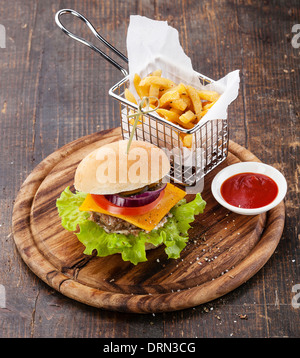 Burger und Pommes frites im Korb auf hölzernen Hintergrund Stockfoto