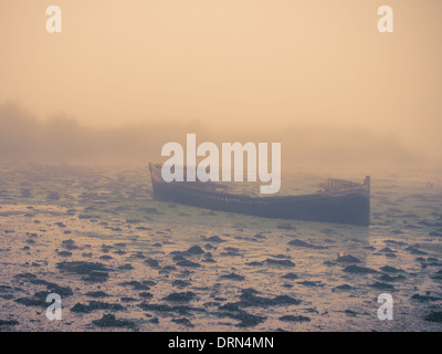 Einem alten Holzboot liegt Fäulnis in den Schlamm in Portsmouth Harbour während einem nebligen Morgen Stockfoto