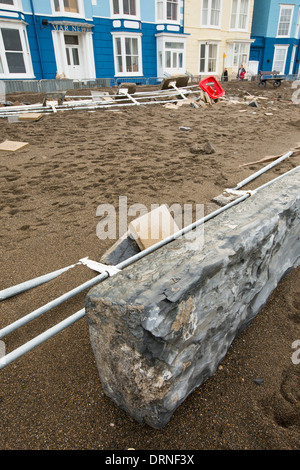 Nach einer Woche der Springfluten, Sturmfluten und Sturmwinde Kraft hat die Strandpromenade von Aberystwyth in Wales, mit Millionen von Pfund Schaden verwüstet. Die brechenden Wellen schlug ein großes Loch in den Deich und ist zusammengebrochen Aberystwyths kultigen, viktorianischen Promenade Unterschlupf, die seit über 100 Jahren stehen geblieben. Dieses Bild entstand auf Mittwoch, 8. Januar 2014, der Tag begann der Rat, zu versuchen, und deaktivieren Sie die Tausende von Tonnen Schutt Strand Meer Offroad. Stockfoto