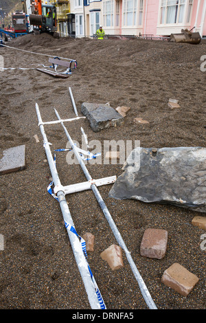 Nach einer Woche der Springfluten, Sturmfluten und Sturmwinde Kraft hat die Strandpromenade von Aberystwyth in Wales, mit Millionen von Pfund Schaden verwüstet. Die brechenden Wellen schlug ein großes Loch in den Deich und ist zusammengebrochen Aberystwyths kultigen, viktorianischen Promenade Unterschlupf, die seit über 100 Jahren stehen geblieben. Dieses Bild entstand auf Mittwoch, 8. Januar 2014, der Tag begann der Rat, zu versuchen, und deaktivieren Sie die Tausende von Tonnen Schutt Strand Meer Offroad. Stockfoto