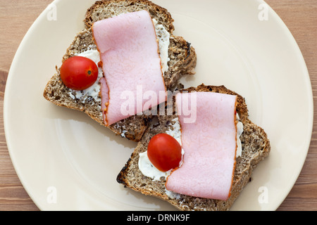 Toast mit Butter, Schinken und Kirschtomaten auf dem Teller. Stockfoto