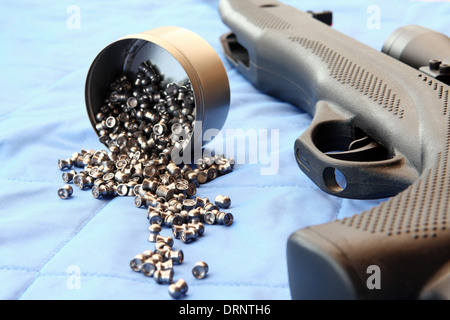 Teil von einem Luftgewehr und einige Pellets auf blauem Hintergrund Stockfoto