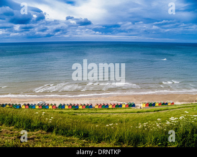 Bunte Strandhütten am Fuße des West Cliff, Whitby, North Yorkshire. Stockfoto