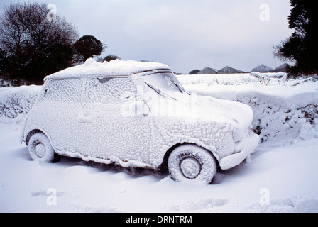 Guernsey. Winter-Szene mit Mini-Auto in Schneeverwehungen stecken. Stockfoto