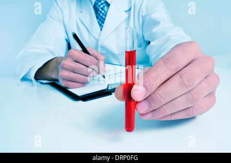 ein Mann mit weißen Mantel mit einer Blutprobe in der hand Stockfoto