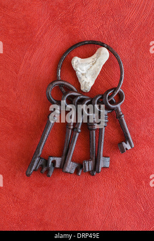Alten Schlüsselbund auf einem roten Hintergrund, Herz aus Stein Stockfoto
