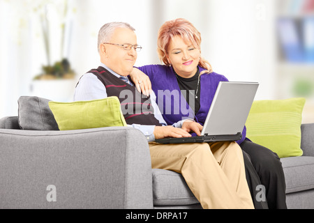 Älteres Paar auf Couch Blick auf Laptop zu Hause sitzen Stockfoto