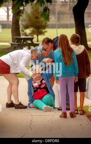 Freunden umgeben eine ältere Frau nach einem Sturz beim Fundraising Spaziergang in Cista Mesa, CA Stockfoto