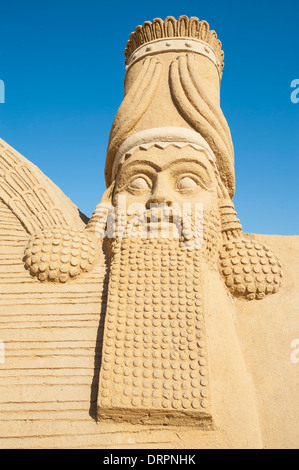 Nahaufnahme Detail große Sand Skulptur Statue der Lamassu Gottheit im Themenpark Sand City vor einem blauen Himmelshintergrund Stockfoto