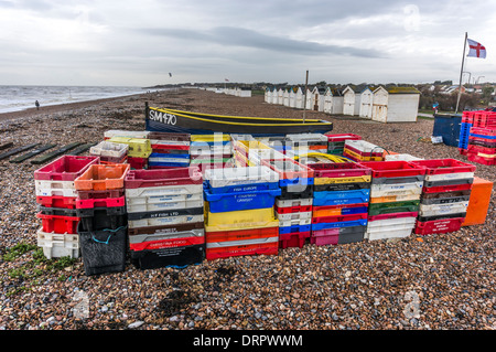 Gestapelte Kisten aus Kunststoff Fische, Boot und Strand Hütten auf Goring-by-Sea Pebble Beach, in der Nähe von Worthing, West Sussex. Stockfoto