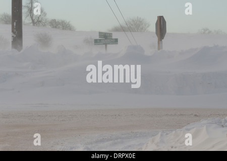Ein Straßenschild Verschluss blockiert eine Fahrbahn nach Fahrzeugen im Wind geblasen, Winterschnee & schweren Winterbedingungen Blizzard verfangen Stockfoto