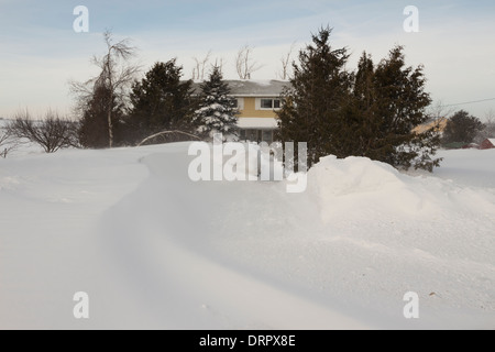 Wind geblasen Schnee schafft große Drifts Abfangen einer Familie in ihrem ländlichen Bauernhof nach Hause nach längeren schweren Winterwetter Stockfoto