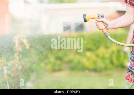 Lifestyle Sommer-Szene. Frau mit Sprinkler Garten Pflanzen gießen. Stockfoto