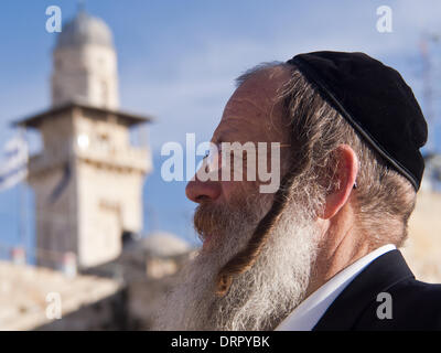 Jerusalem, Israel. 31. Januar 2014. Ein Ultra-orthodoxer jüdischer Mann mit langen Seite sperren und eine Kippa auf dem Kopf betrachtet an der Klagemauer Platz mit muslimischen Moschee Minarett im Hintergrund. Jerusalem, Israel. 31. Januar 2014.  Juden aller feierten Anfang des hebräischen Monats von Adar I bei der Kotel, die Klagemauer. Bildnachweis: Nir Alon/Alamy Live-Nachrichten Stockfoto