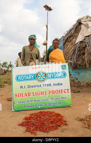 Eine unantastbare Familie vor ihrer Hütte, beleuchtet durch elektrisches Licht, angetrieben von einem A4 große Solar-panel Stockfoto