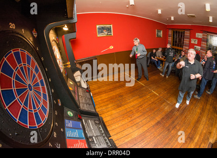 Pfeile fliegen in Richtung der Dartscheibe in einer Kneipe. Stockfoto