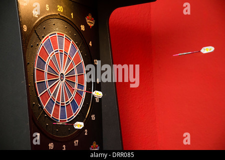 Pfeile fliegen in Richtung der Dartscheibe in einer Kneipe. Stockfoto