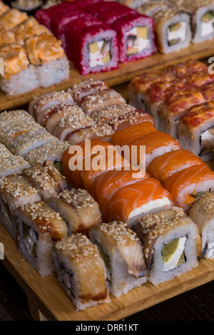 Sortiment-Sushi und Rollen auf Holzplatte in dunkles Licht Stockfoto