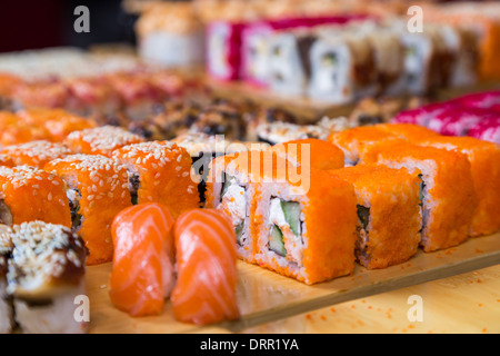 Sortiment-Sushi und Rollen auf Holzplatte in dunkles Licht Stockfoto