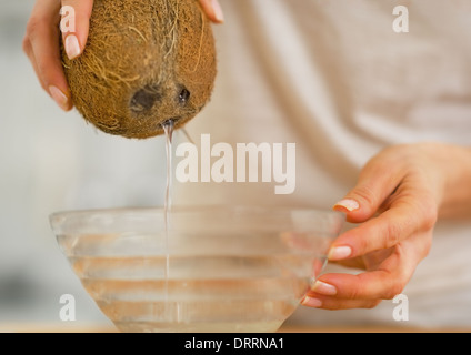 Closeup auf junge Frau, die Kokosmilch in Teller gießen Stockfoto