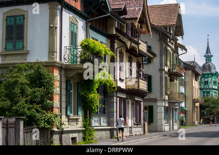 Jogger geht traditionelle Häuser in Neugasse in Interlaken im Berner Oberland, Schweiz Stockfoto