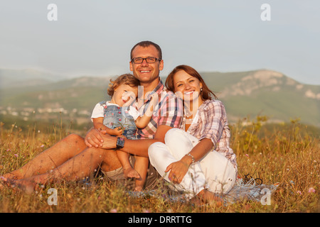 Glückliche Mutter, Vater und Tochter im Sonnenuntergang Stockfoto