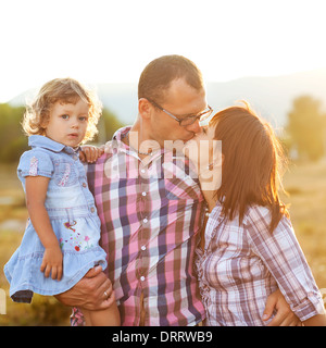 Glückliche Mutter, Vater und Tochter im Sonnenuntergang Stockfoto
