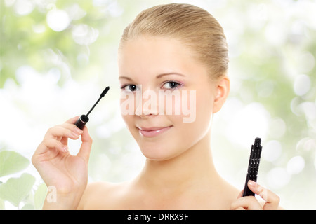 Mädchen, die Anwendung von Mascara auf grünem Hintergrund Stockfoto