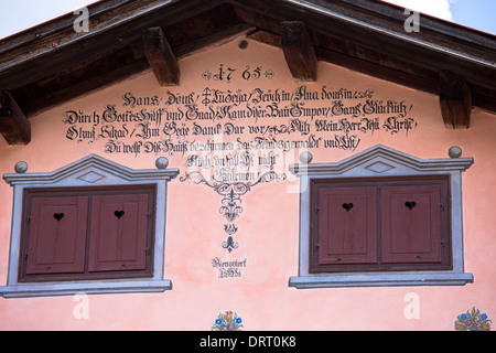 Fensterläden, Inschrift und Farbeffekte im 18. Jahrhundert Haus gebauten 1765 in Klosters, Graubünden, Schweiz Stockfoto