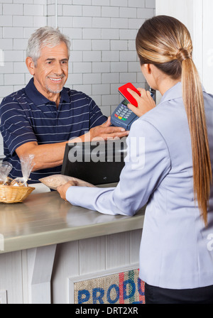 Weibliche Kunden zahlen über Mobiltelefon im Store Stockfoto